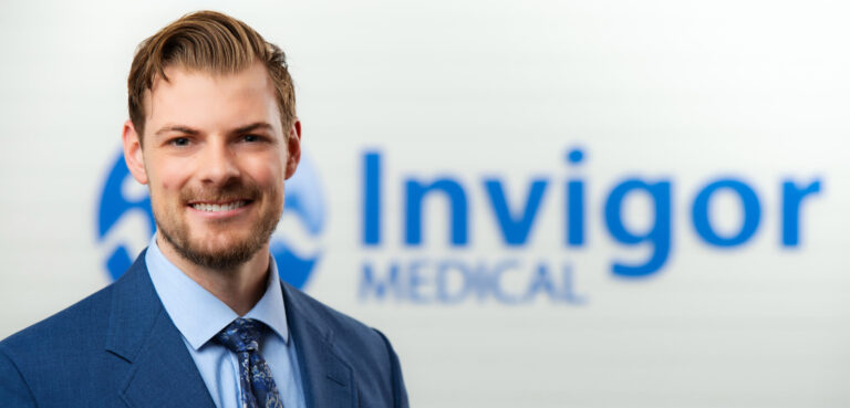 Derek Berkey in front of Invigor Medical Sign